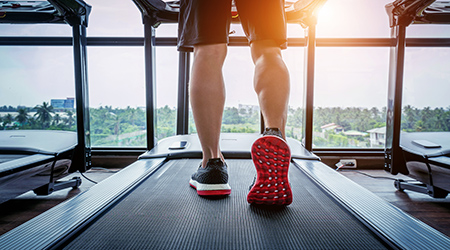 Male feet in sneakers running on the treadmill at the gym. Exercise concept.
